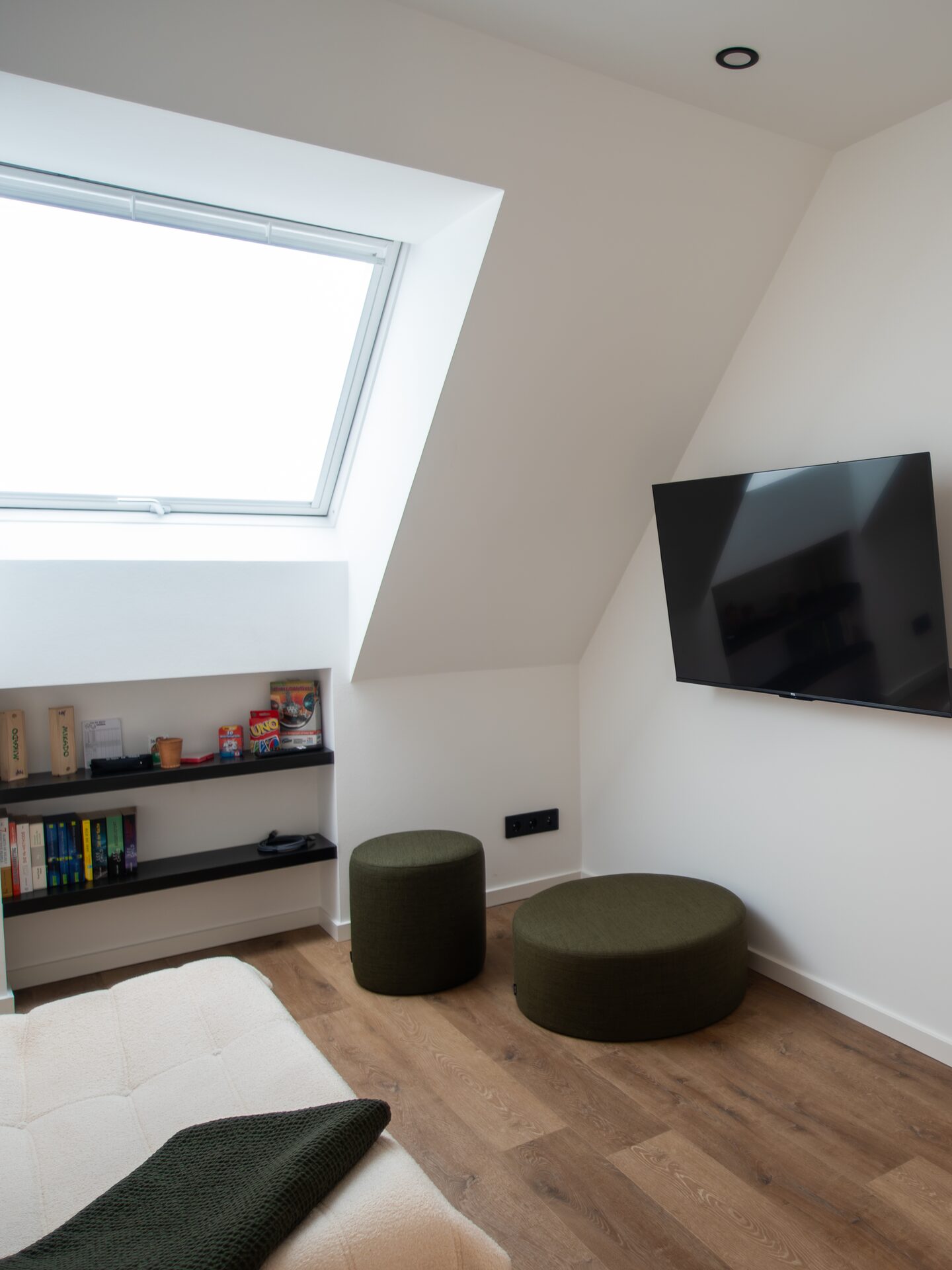 Loft-Lounge unterm Dach mit Dachfenster, Spieleregal und Sitzhockern