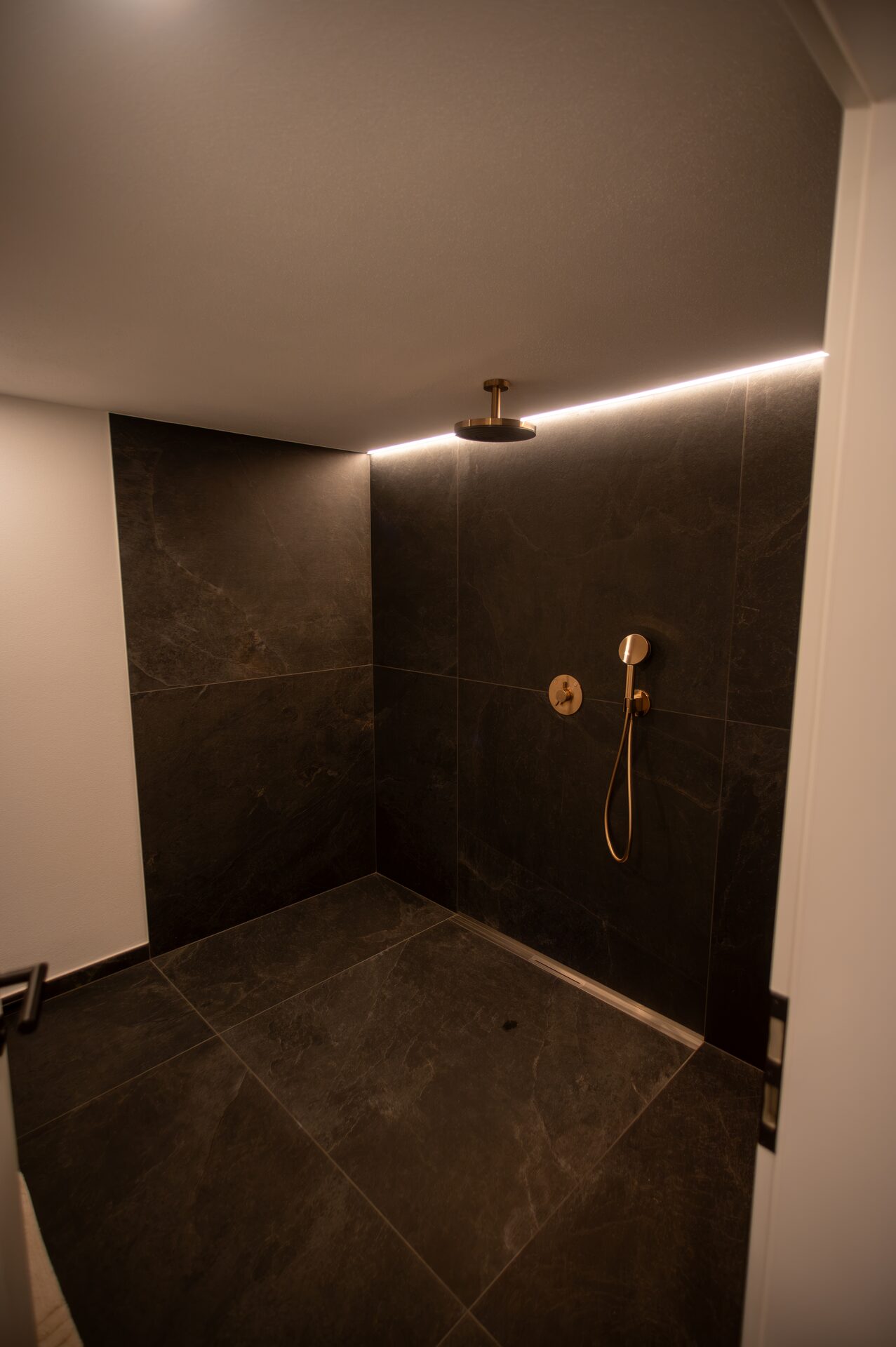 Bodentiefe Regendusche mit dunklem Schiefer und Bronze-Armatur