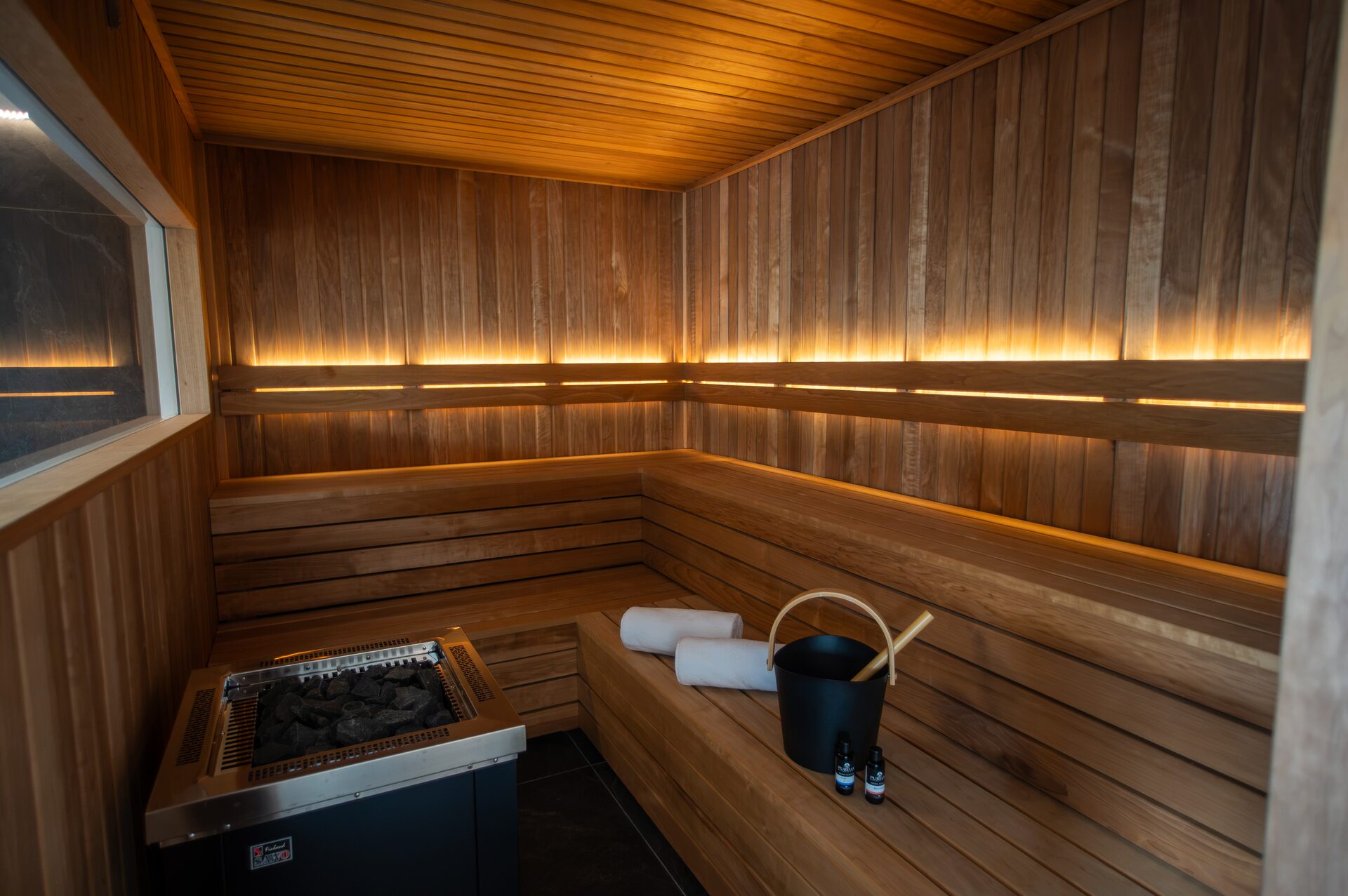 Sauna aus Thermo-Espe mit Saunaofen, Aufgusskübel und gerollten Handtüchern