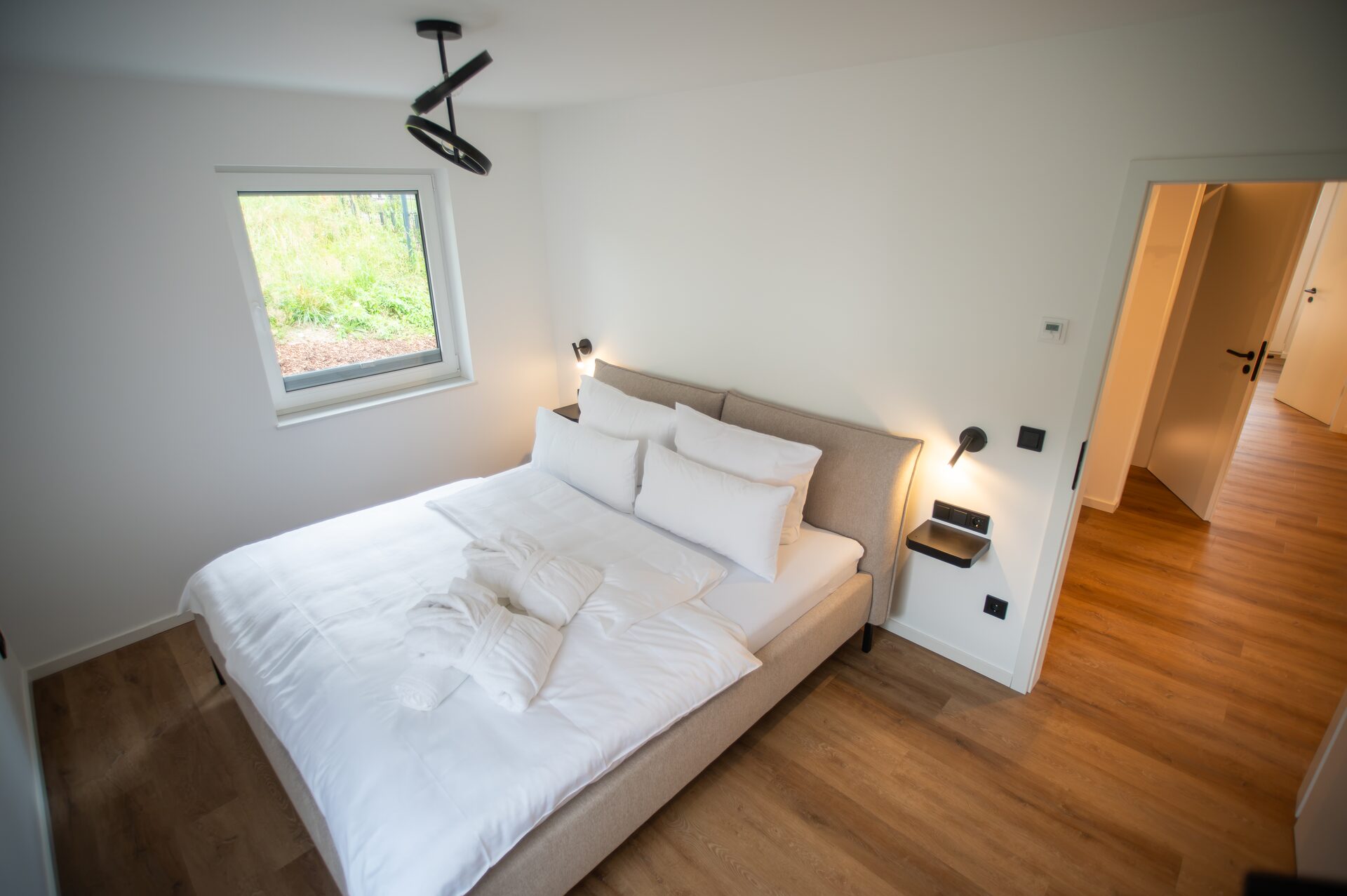 Doppelbett mit weißer Bettwäsche und gepolstertem Kopfteil