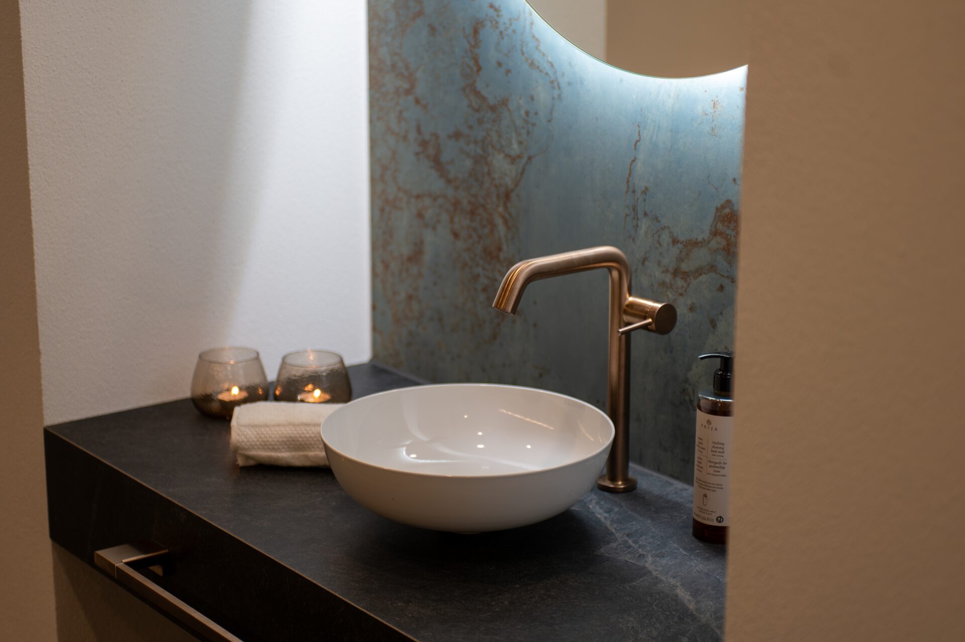 Weißes Aufsatzbecken mit Bronze-Armatur und Teelichtern
